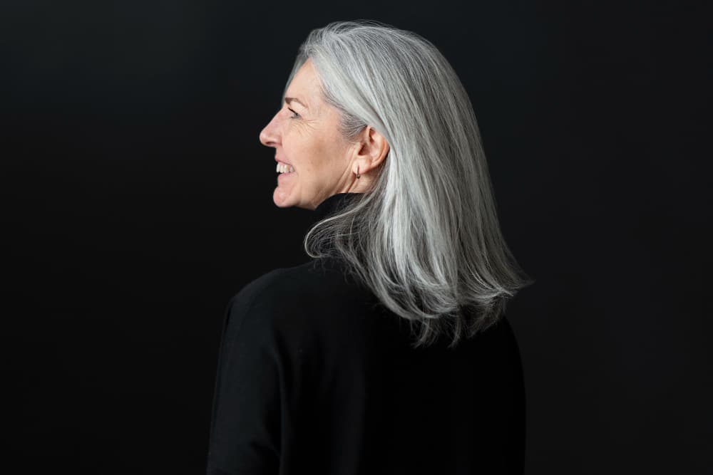 Mujer con cabello blanco largo y brillante cuidado con champú específico para canas