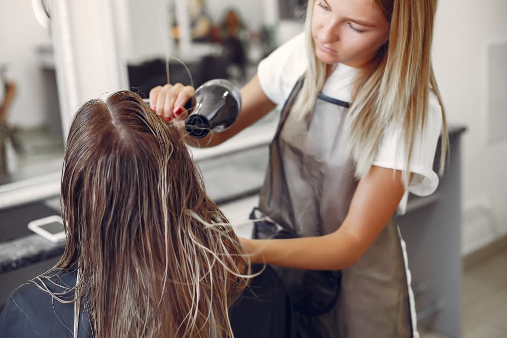 Profesional de peluquería utilizando productos de cosmética profesional en un salón de belleza