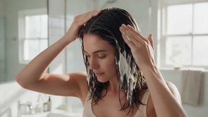 Mujer aplicando mascarilla hidratante Milano Cosmetics en cabello sano y brillante